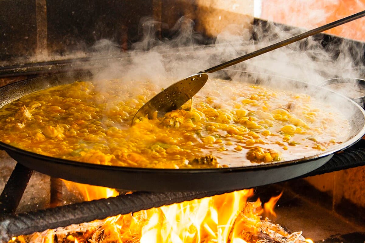 Paella fumante cuisinée sur le feu de bois