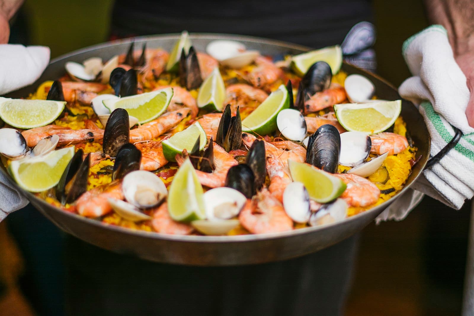 Paella géante aux fruits de mer présentée à deux mains